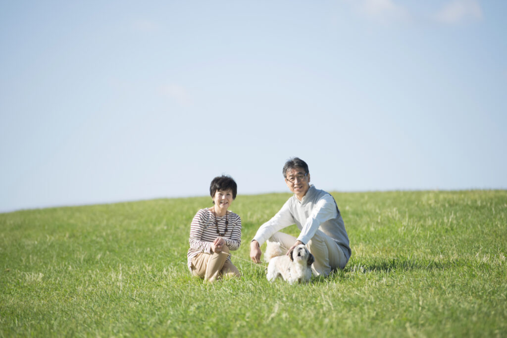 草原に座る夫婦と犬